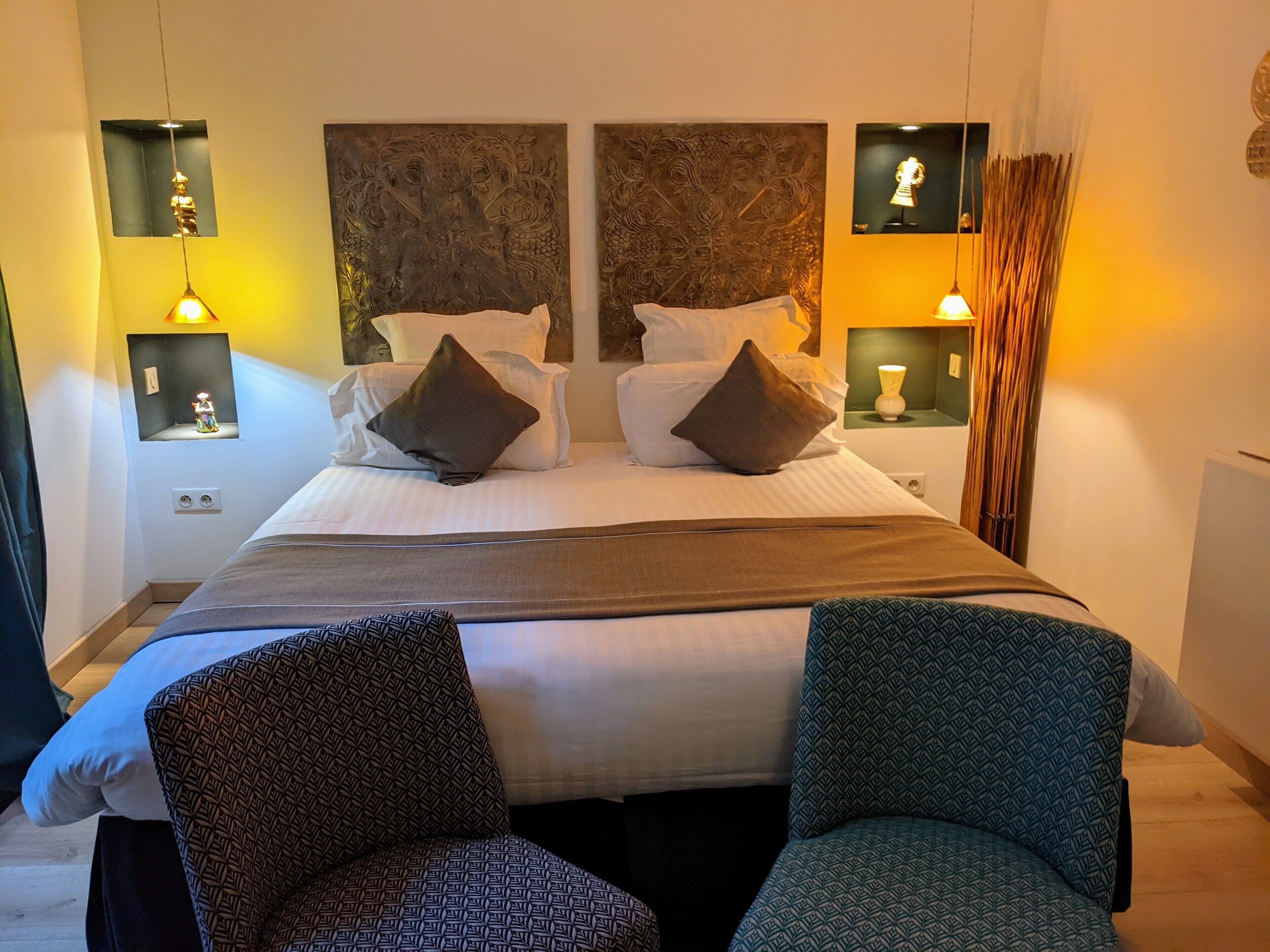A hotel room with a large bed, two nightstands, a mirror, and two chairs.