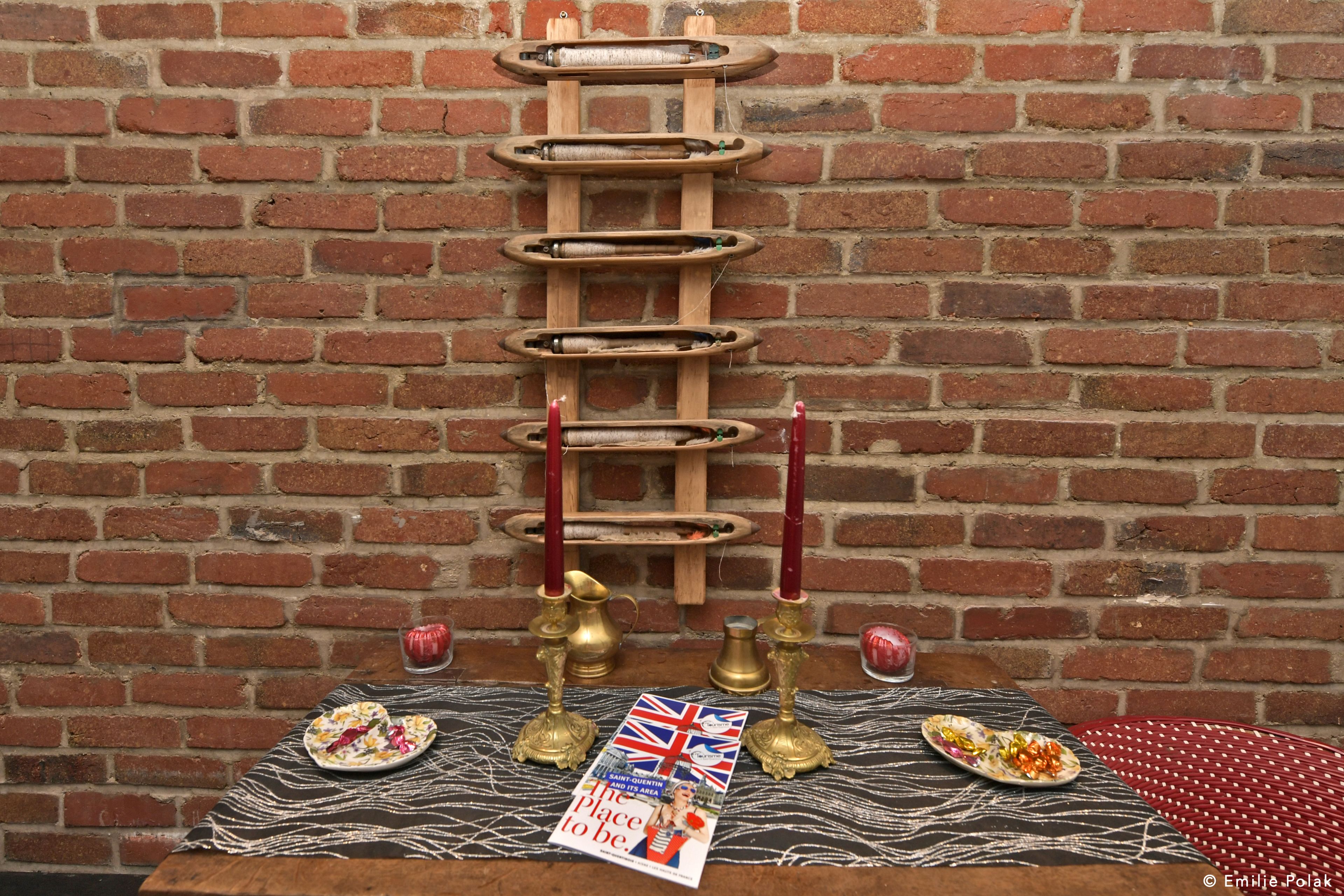Una mesa con platos de comida, una revista y una escalera de madera apoyada en una pared de ladrillo.