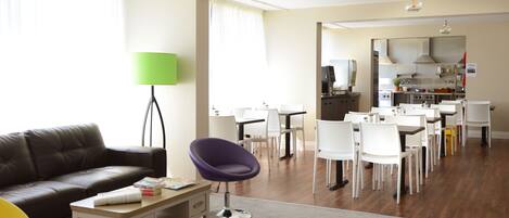 A modern living room with a leather sofa, a purple chair, and a dining area with white chairs and a table.