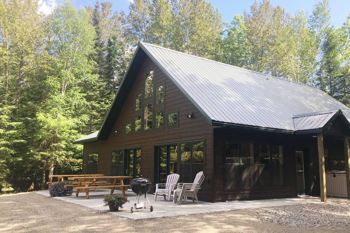 A cabin with a sloped roof, large windows, and a covered porch area.