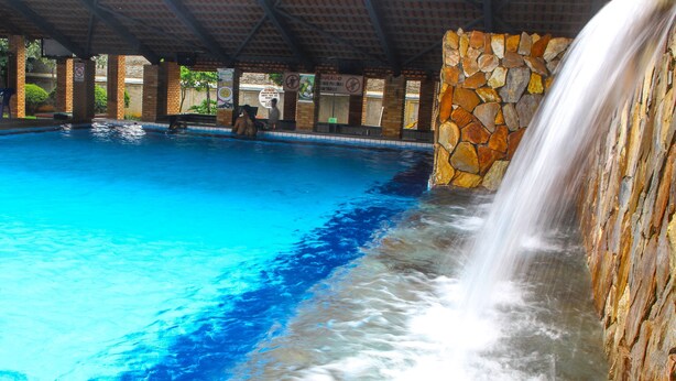 A pool with a stone wall and a waterfall feature.