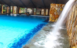A pool with a stone wall and a waterfall feature.