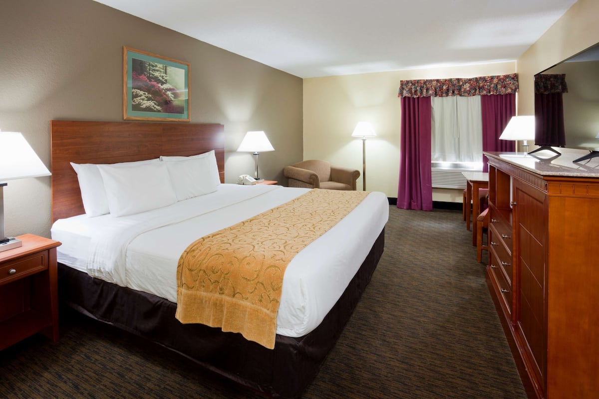 Une chambre d’hôtel avec un grand lit, une commode en bois, un bureau et une chaise.
