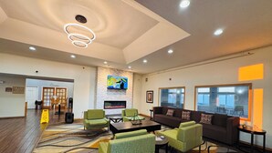 A spacious lobby with a fireplace, comfortable seating, and a large TV screen.