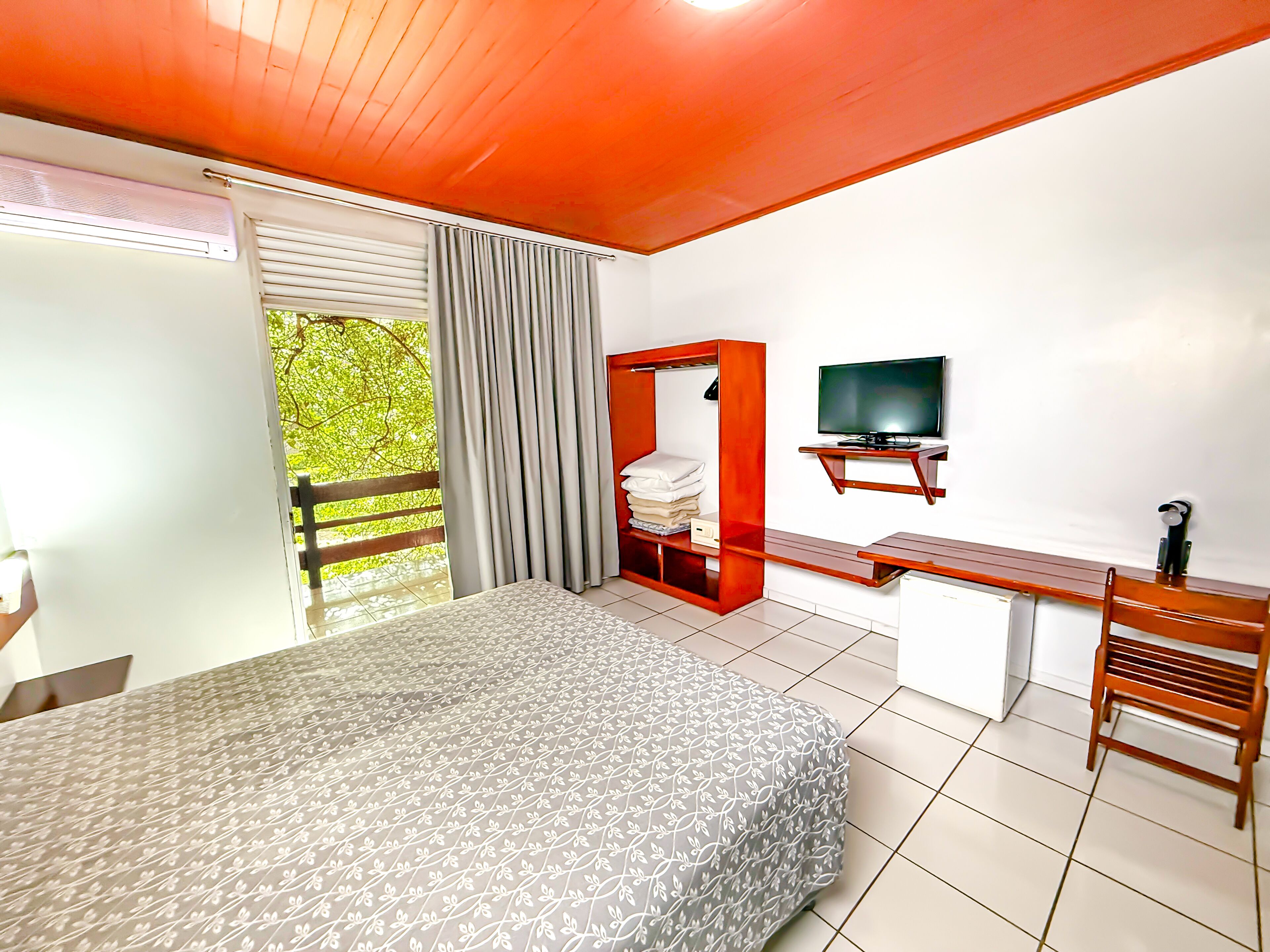 A bedroom with a bed, a desk, a TV, and a wardrobe.