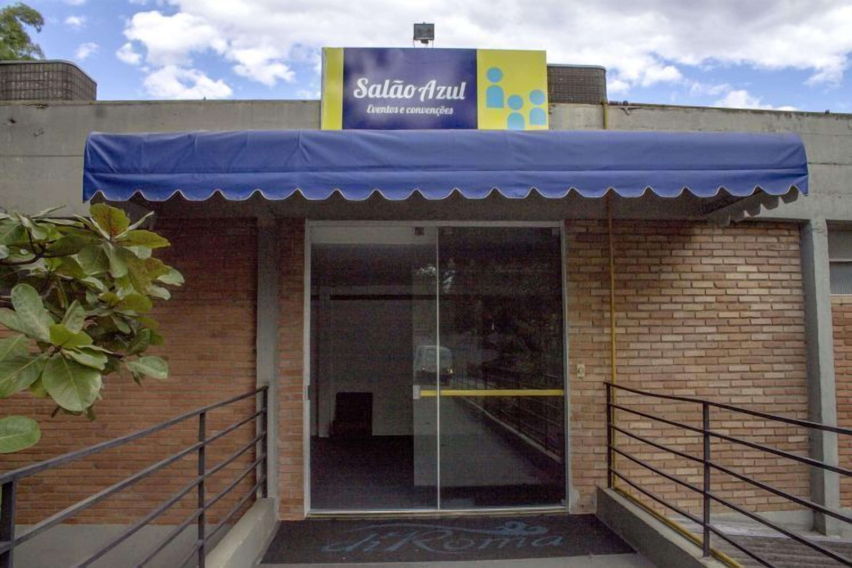 A building entrance with a blue awning, a glass door, and a sign above reading 'Salão Azul Eventos e convenções.'