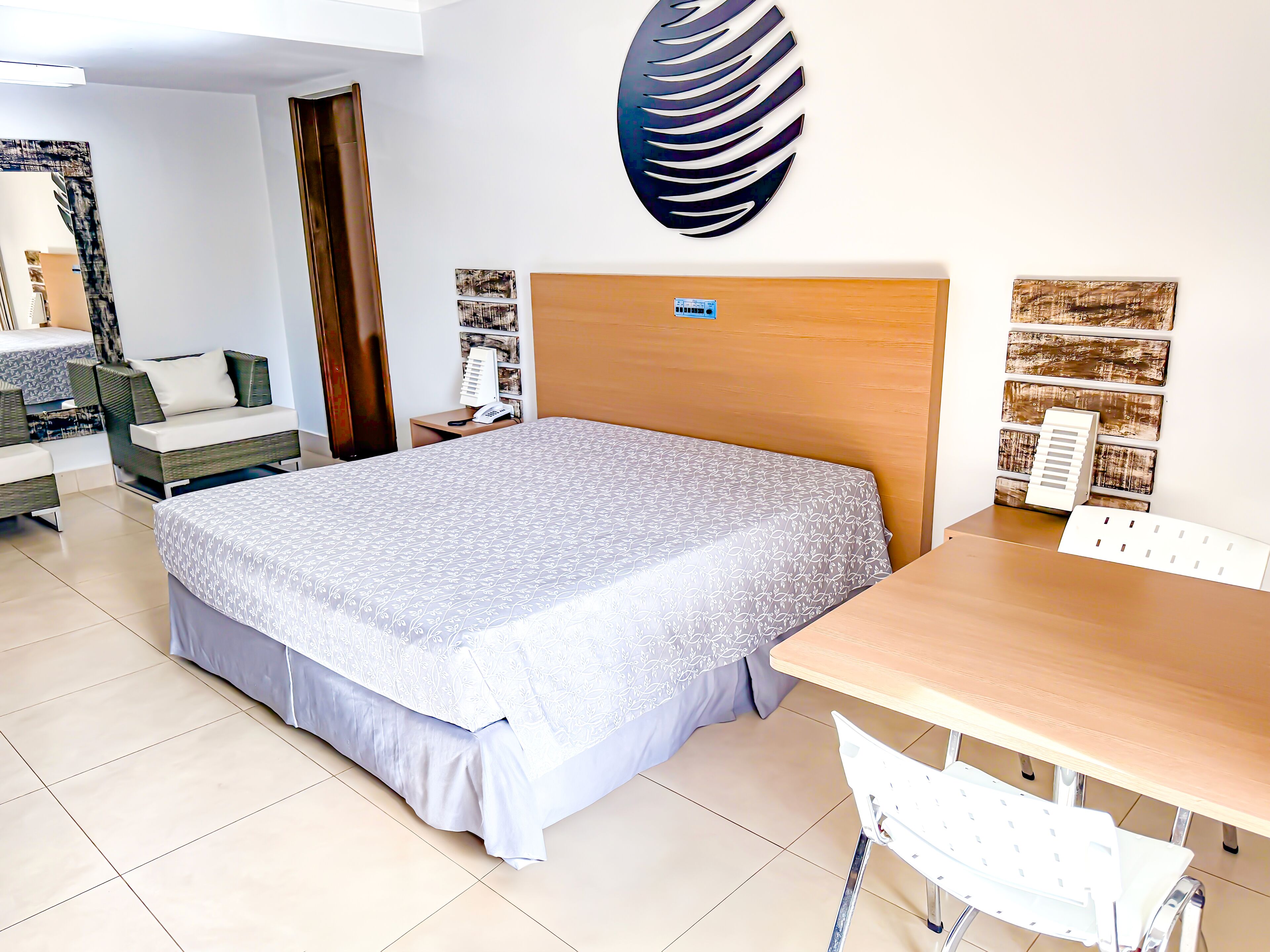Habitación de hotel con cama, mesita de noche, lámpara y un adorno en la pared.