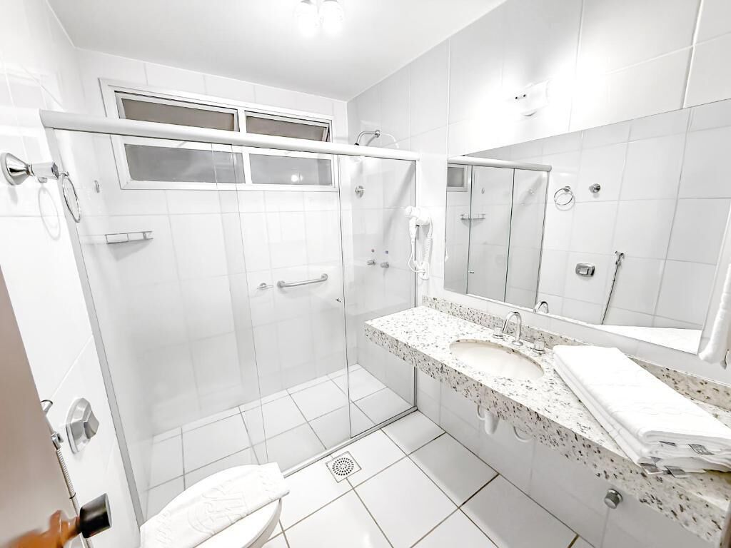 A modern bathroom with a glass shower enclosure, a sink with a marble countertop, and a large mirror.