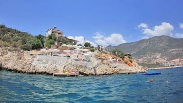 A coastal property with a rocky outcrop, a dock, and a building with a balcony overlooking the sea.
