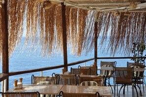An outdoor dining area with wicker furniture and a view of the sea. - Caretta Hotel (Kas)