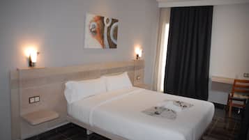 A hotel room with a large bed, bedside tables, a desk, and a chair.