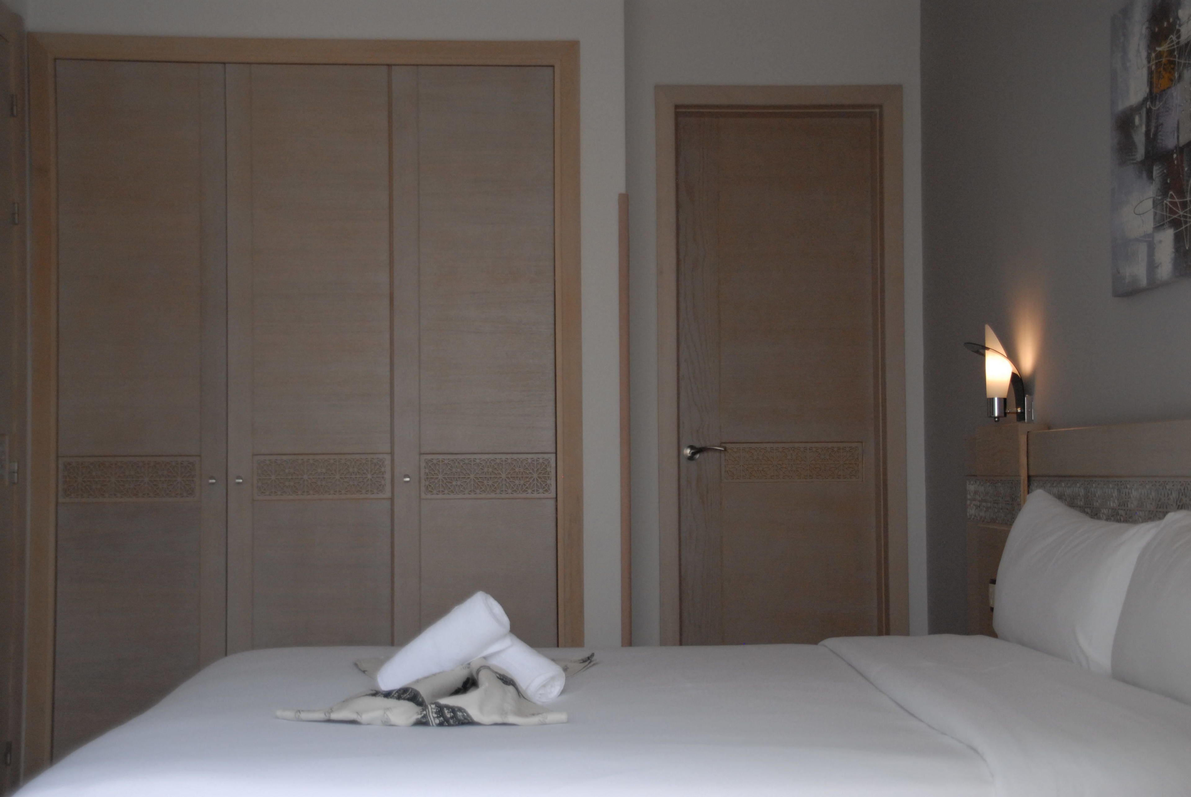 A hotel room with a bed, a wardrobe, and a door.