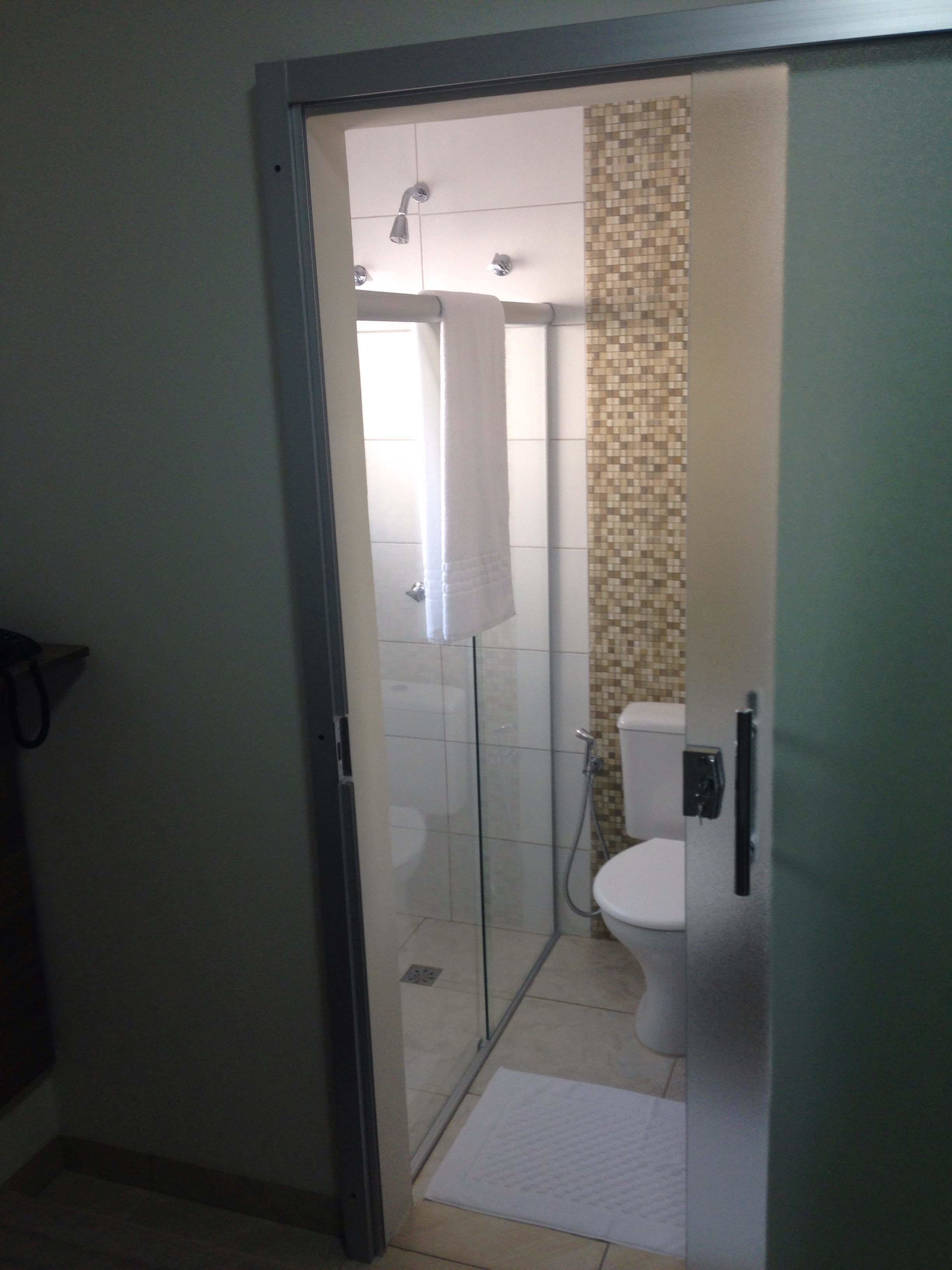 Un bagno con box doccia in vetro, un water e una parete doccia rivestita di piastrelle.