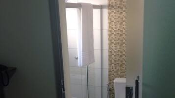 Un bagno con box doccia in vetro, un water e una parete doccia rivestita di piastrelle.