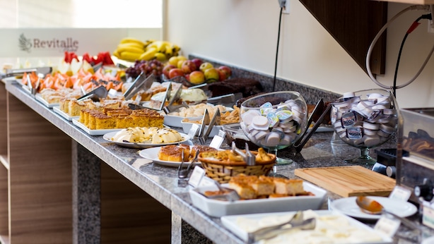 Un bufé con diversos alimentos, entre ellos frutas, pasteles y carnes.