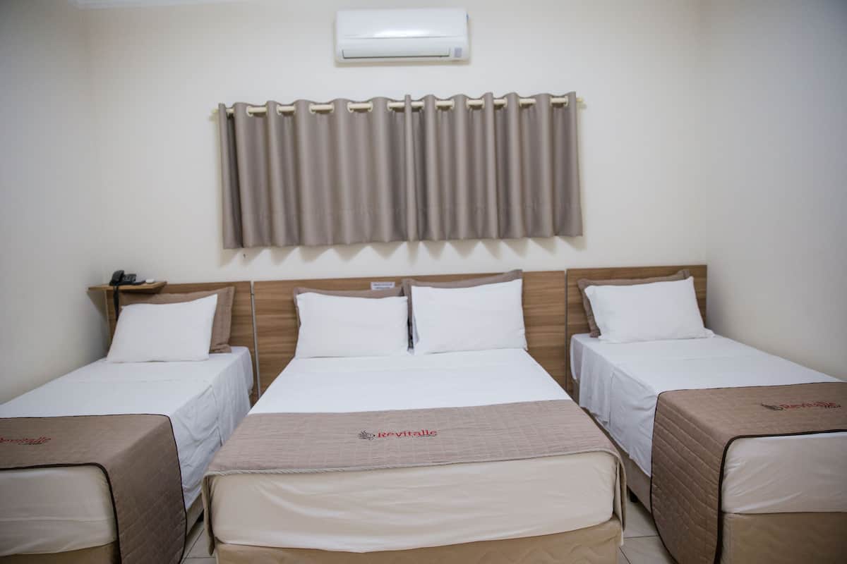 Ein Hotelzimmer mit zwei Einzelbetten, einem Doppelbett und einem kleinen Tisch.