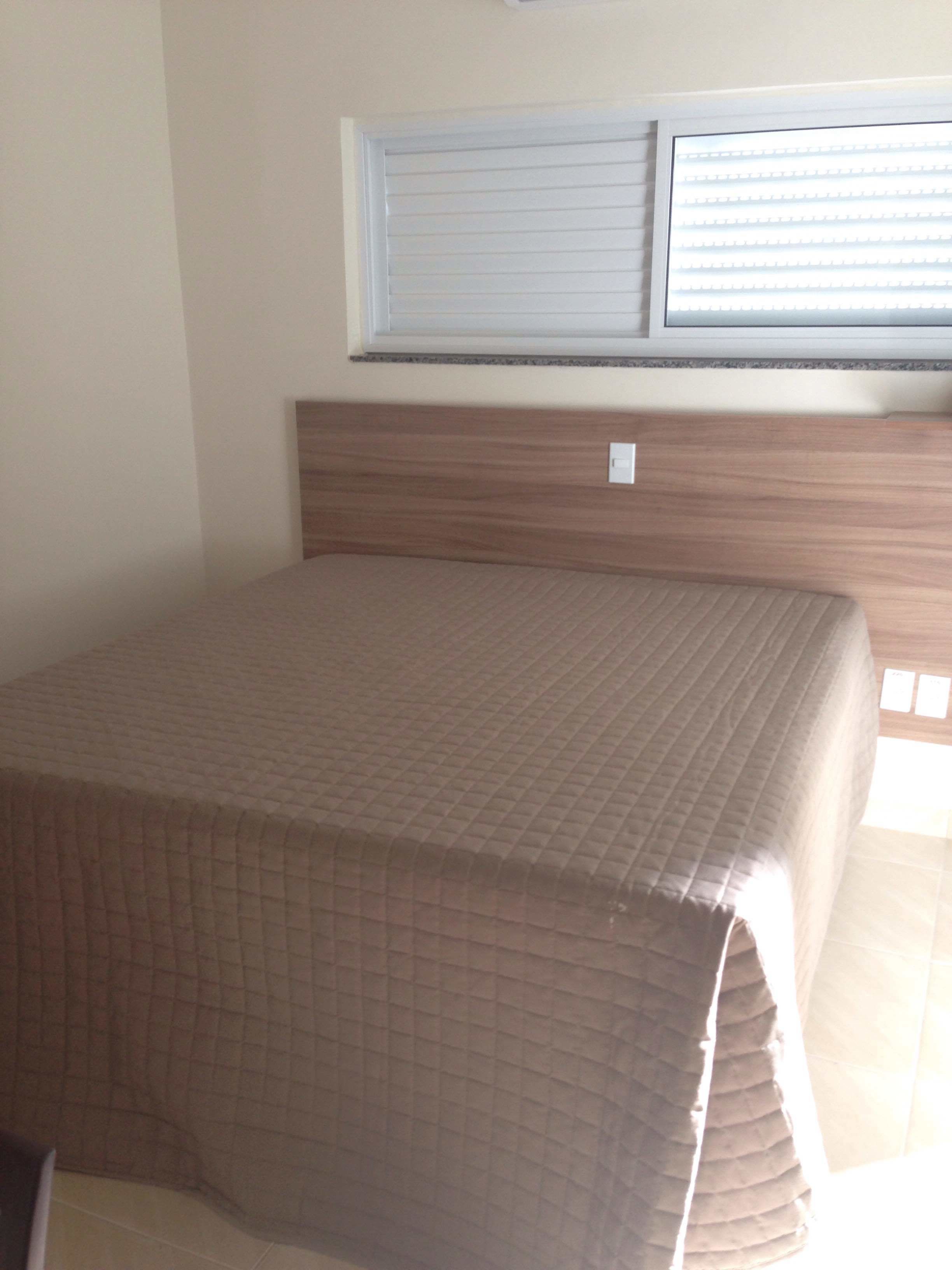 Una habitación con cama, ventana con persianas y cabecera de madera.