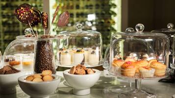 Verschiedene Desserts auf Glasständern und Schalen präsentiert, darunter Kuchen, Kekse und Gebäck.