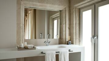 Un baño moderno con un espejo grande, un lavamanos blanco y un perchero.