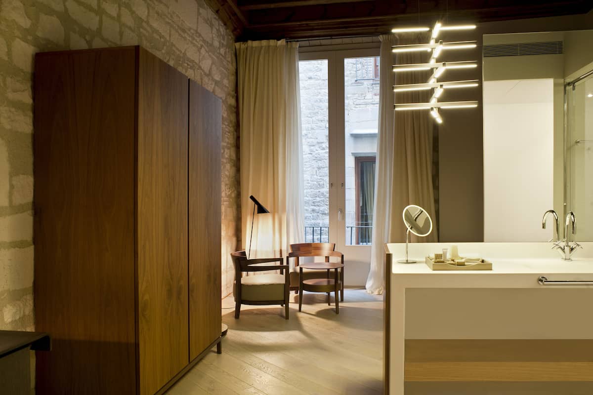 A modern bathroom with a wooden wardrobe, a round mirror, and a large window with curtains.