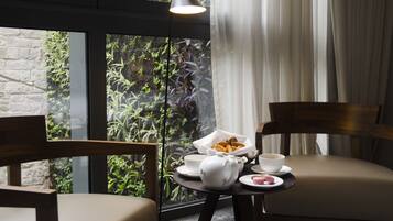 A cozy seating area with a table set for two, featuring a coffee cup, pastries, and a teapot.