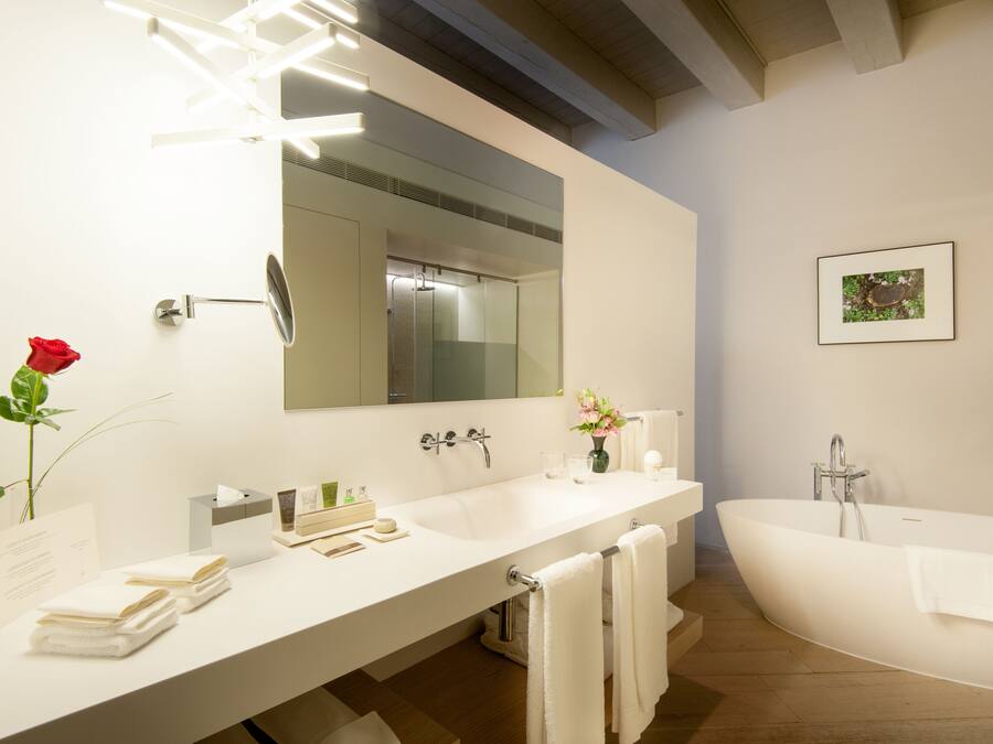 Un baño moderno con un espejo grande, una bañera blanca y un tocador con lavamanos y toallero.