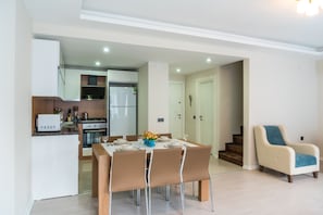 Une cuisine moderne avec un coin repas, un canapé et un escalier.