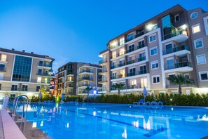 Un hôtel moderne doté d’une piscine, de nombreux balcons et de grandes fenêtres bien éclairées.