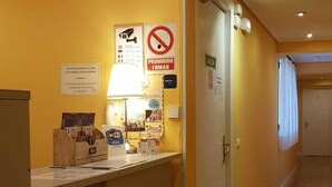 A reception area with a desk, a no-smoking sign, and a sign indicating the exit. - Pensión Bilbao (Bilbao)