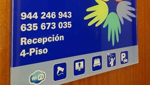 A blue sign with contact information for Pension Bilbao, including two phone numbers and a website URL. - Pensión Bilbao (Bilbao)