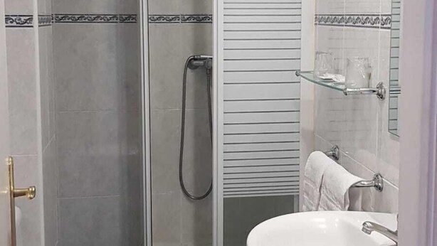 Un baño con inodoro, ducha con mampara de vidrio y lavamanos.