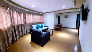 Un salón espacioso con un sofá azul oscuro, una mesita de centro y una zona de comedor con sillas de madera.