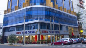 Un hotel de varios pisos con fachada de vidrio moderna y señalización que indica 'SWAN HOTEL' y 'CHIFA YING CHENG'.