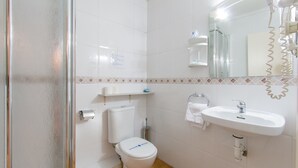 Une salle de bain avec des toilettes, un lavabo et une douche.