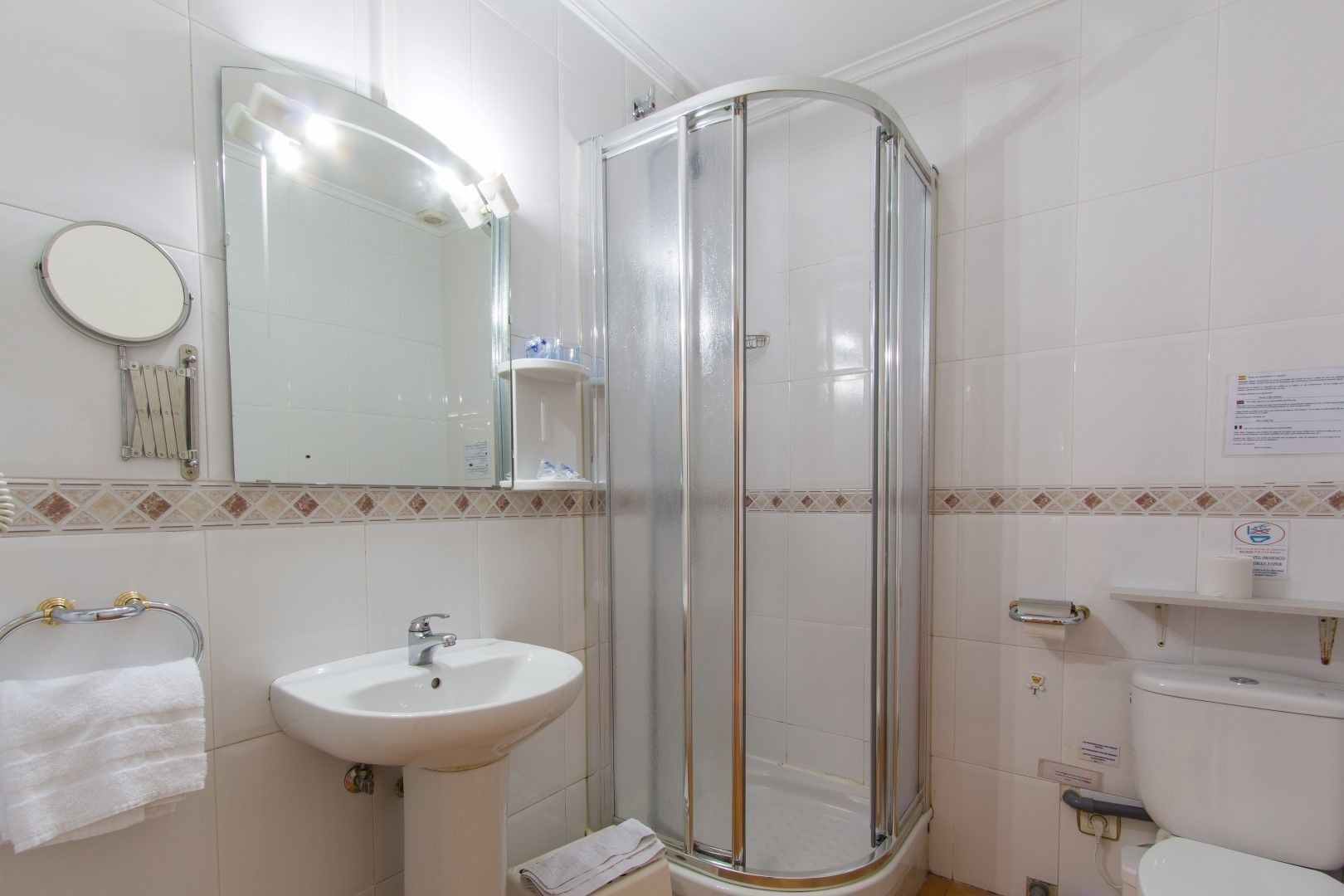 Une salle de bain avec une douche à parois de verre, un lavabo, un miroir et des toilettes.