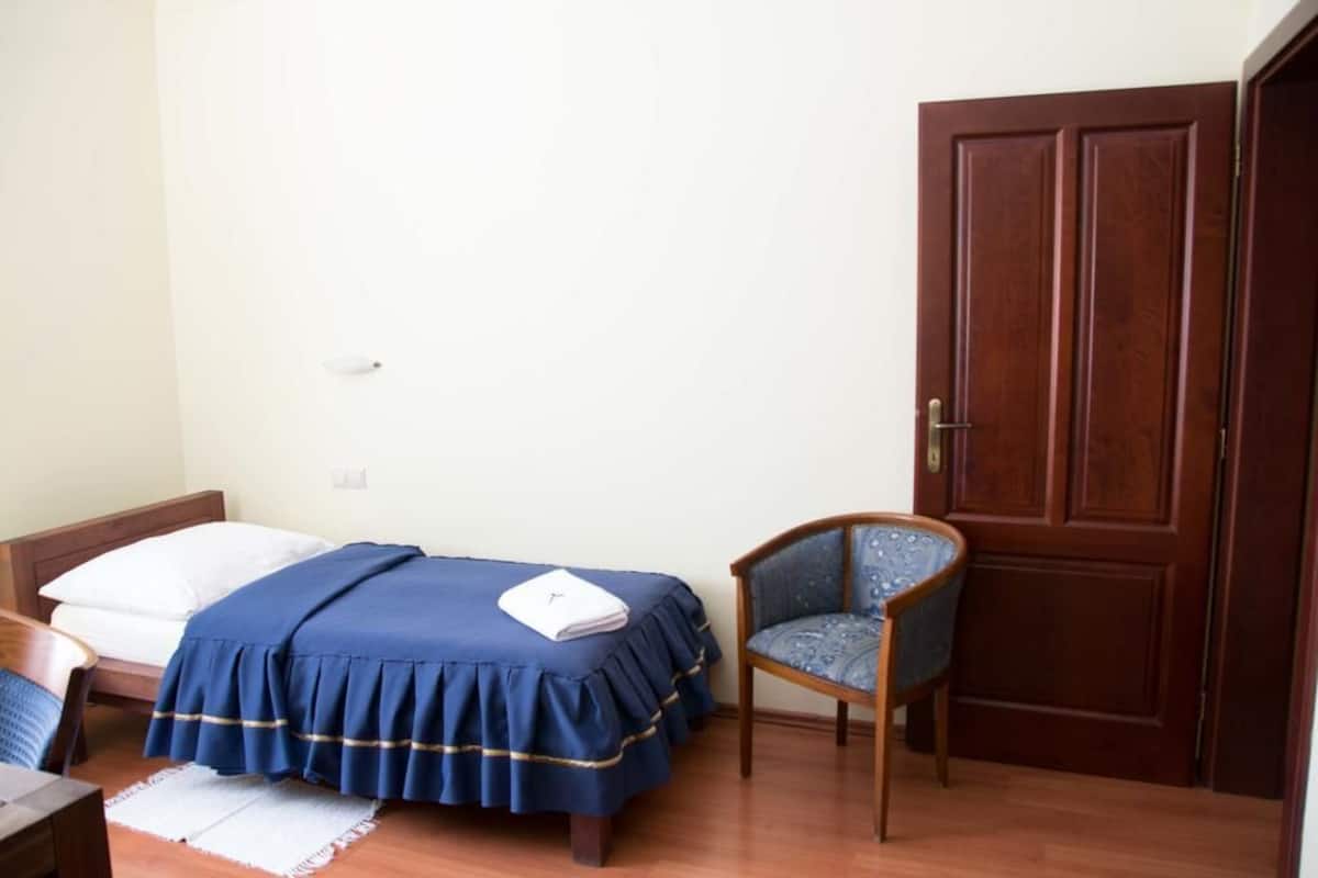 Une chambre à coucher avec un lit, une chaise, une porte en bois et une petite table.