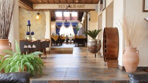 Un hall d’entrée avec une table basse en bois, des canapés en cuir noir et un panneau indiquant l’emplacement d’un restaurant.