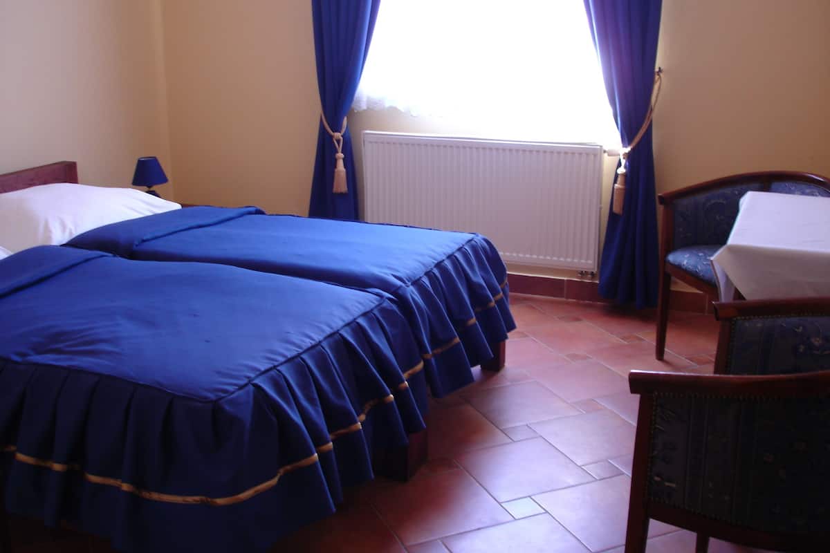 Une chambre avec deux lits, une chaise, une table et une fenêtre avec des rideaux.
