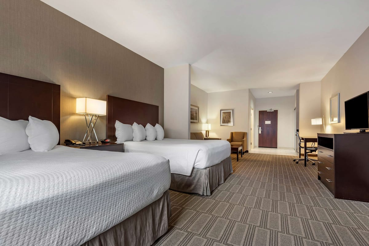 A hotel room with two beds, a desk, a chair, a TV, and a wardrobe.