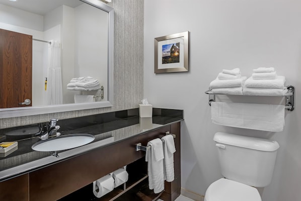 Un baño con lavamanos, espejo, toallero y retrete.