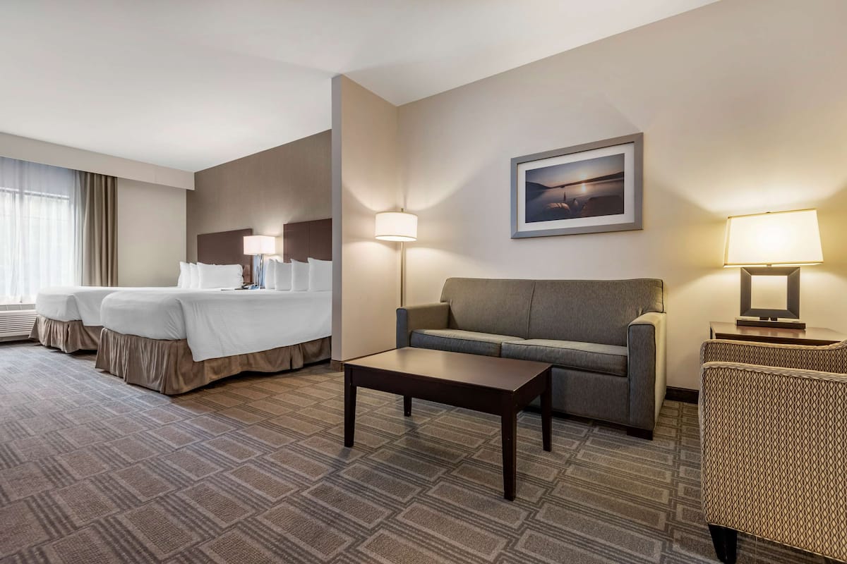 A hotel room with a large bed, a sofa, a small table, and two lamps.
