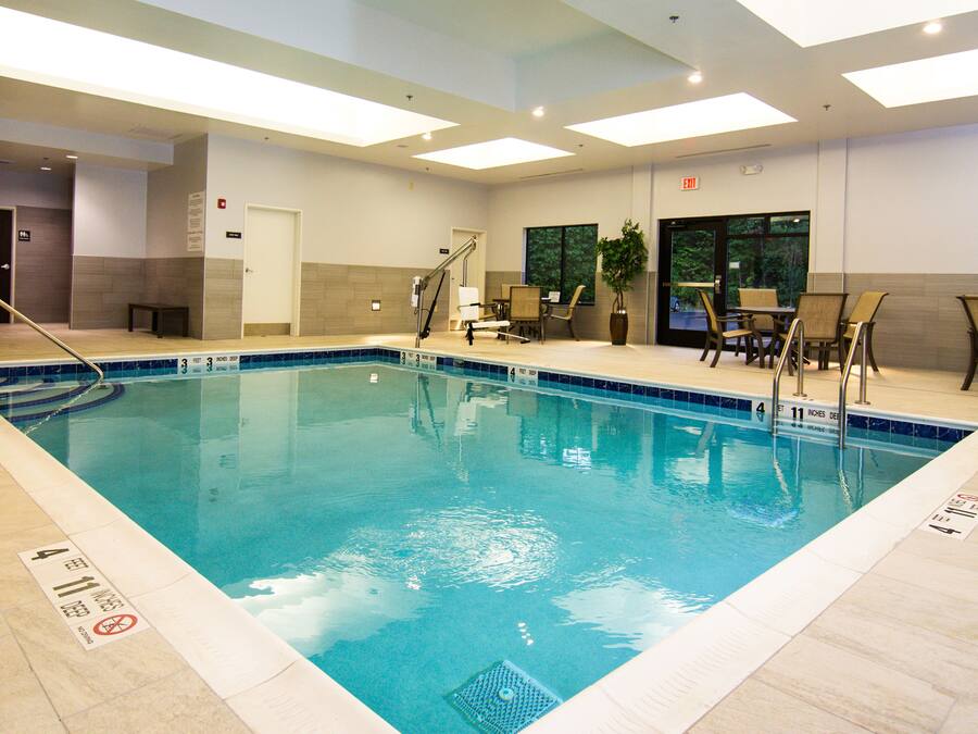 An indoor swimming pool with clear water, surrounded by lounge chairs and a seating area.