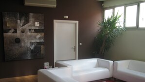A modern living room with a white sofa, a red carpet, and a large abstract painting on the wall. - Bilbao Central Hostel (Bilbao)