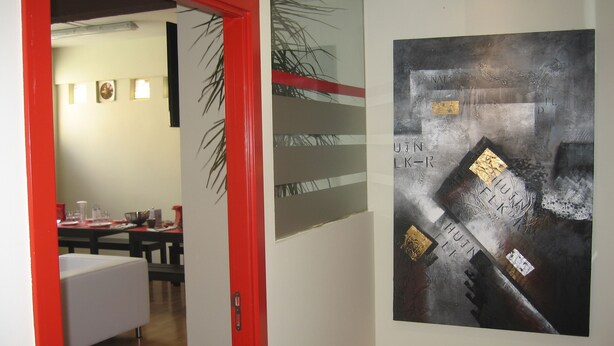 A modern interior with a dining area, a red-framed door, and a large abstract painting on the wall. - Bilbao Central Hostel (Bilbao)