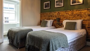 A room with two beds, a wooden headboard, and framed pictures on the wall. - The First Hurdle Guest House (Chepstow)