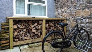 A bicycle parked next to a wooden bench with a stack of firewood. - The First Hurdle Guest House (Chepstow)