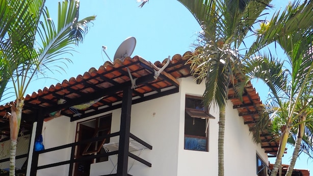 Un edificio de dos pisos con una antena parabólica, un balcón y una pequeña escalera que conduce a la entrada.