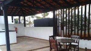 Un patio techado con piscina, una mesa con sillas y un extintor.
