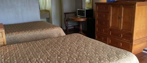 A hotel room with two beds, a wooden dresser, a television, and a mirror.