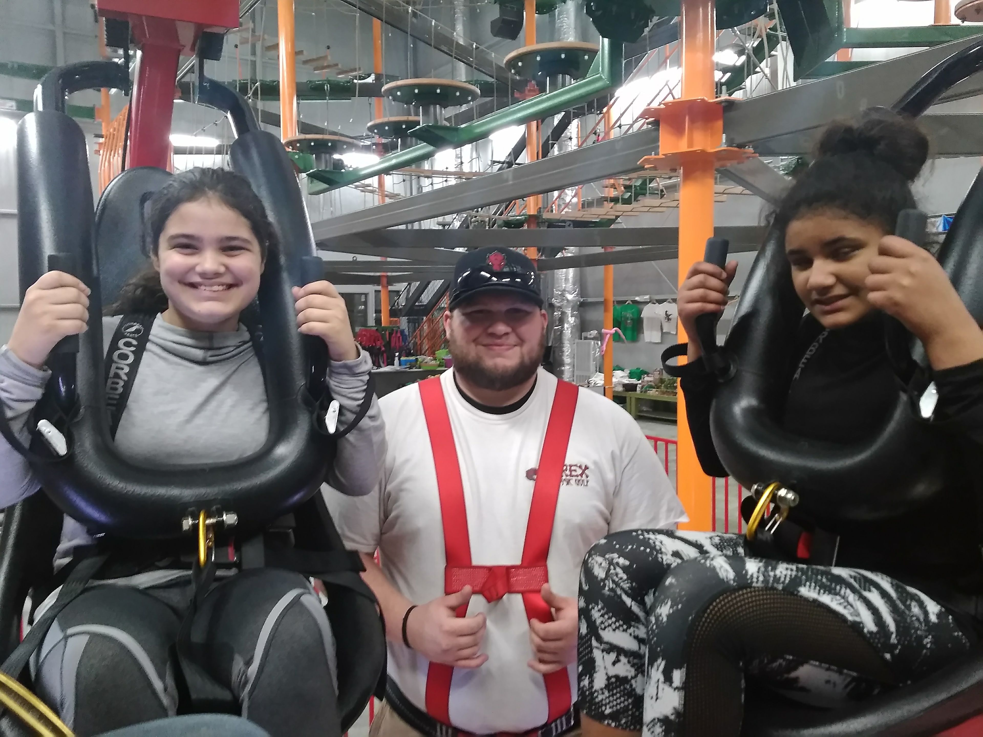 A person in a white shirt with red suspenders and a cap, holding a steering wheel.